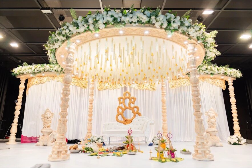 Weiss-goldenes rundes Mandapam mit weissen Blumen in einer Halle